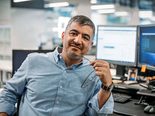 Asian Middle Eastern businessman sitting in office with eyeglasses and computer terminal